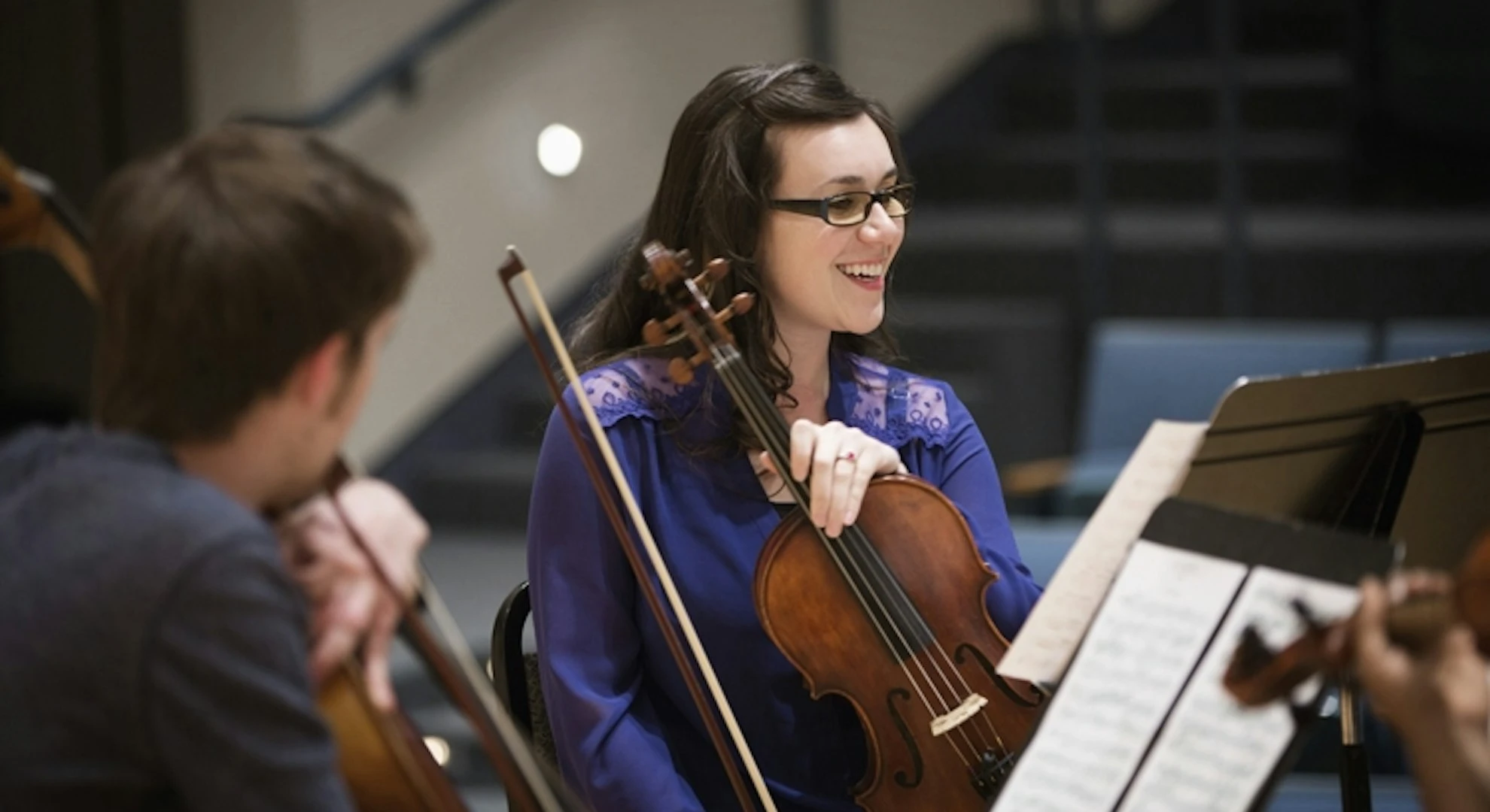 smiling-female-violinist-at-orchestra-rehearsal.webp