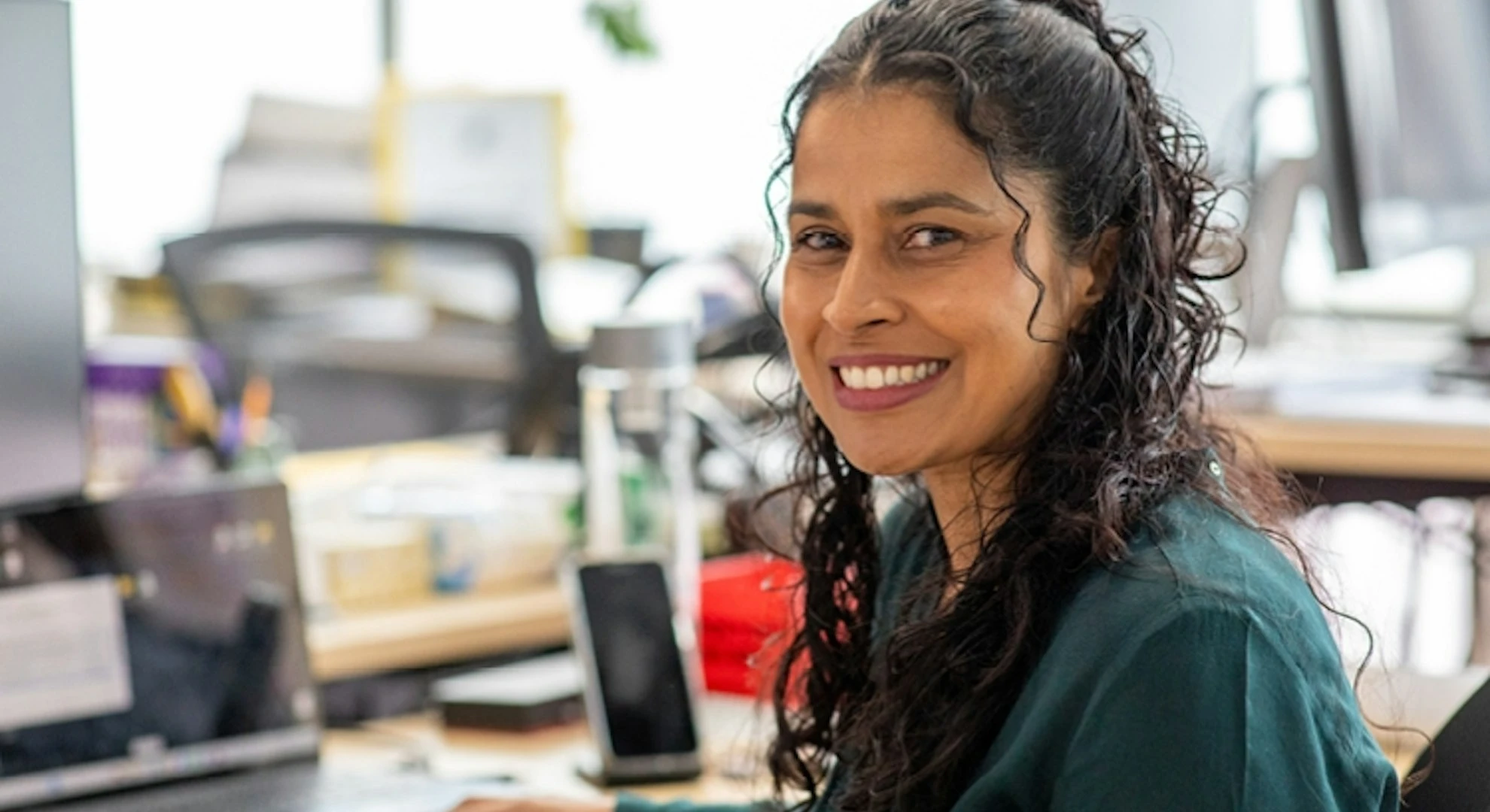 smiling-professional-woman-in-office-workspace.webp
