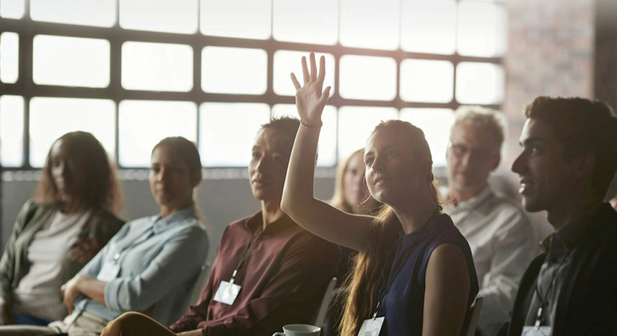 woman-raising-hand-asking-question-at-business-conference.webp